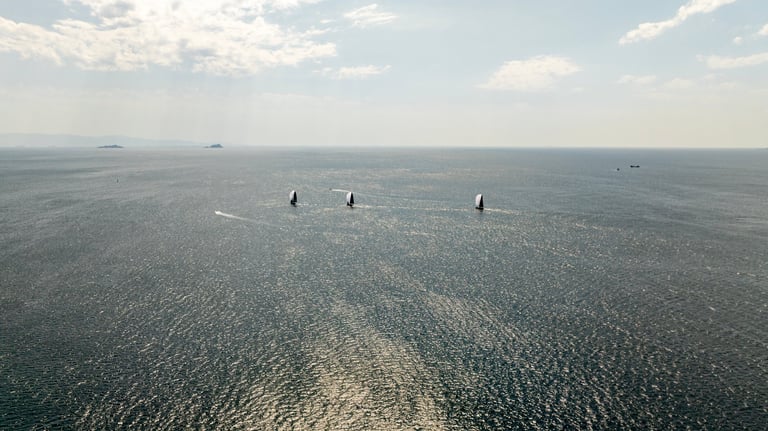 Multiple sailboats navigating in harmony across open blue Mediterranean waters