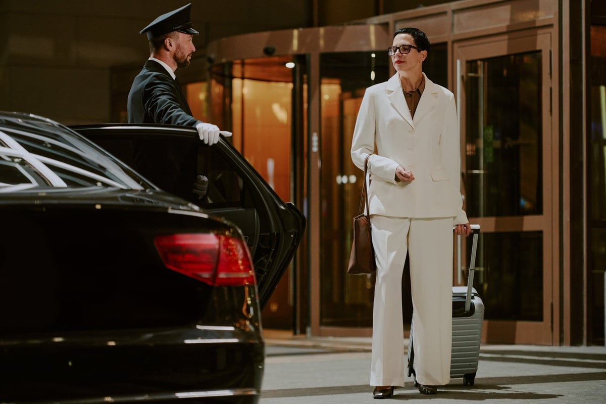 Chauffeur in uniform opening a car door for a guest at a hotel entrance