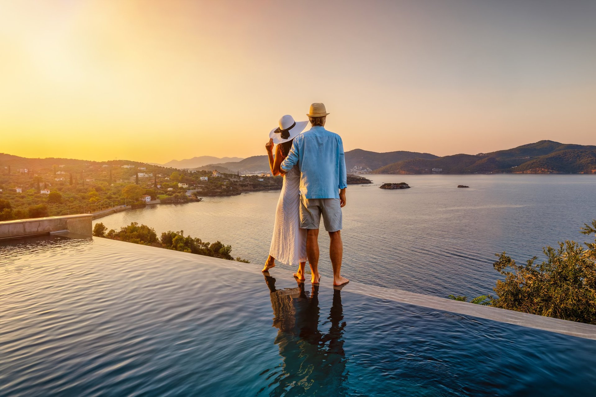 Couple on summer vacation by the pool at sunset over the Mediterranean sea