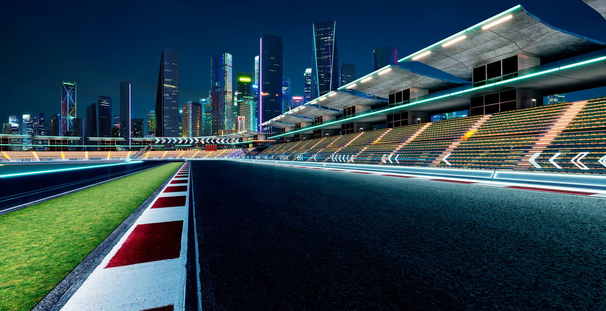 Racetrack circuit with grandstands and cityscape at evening