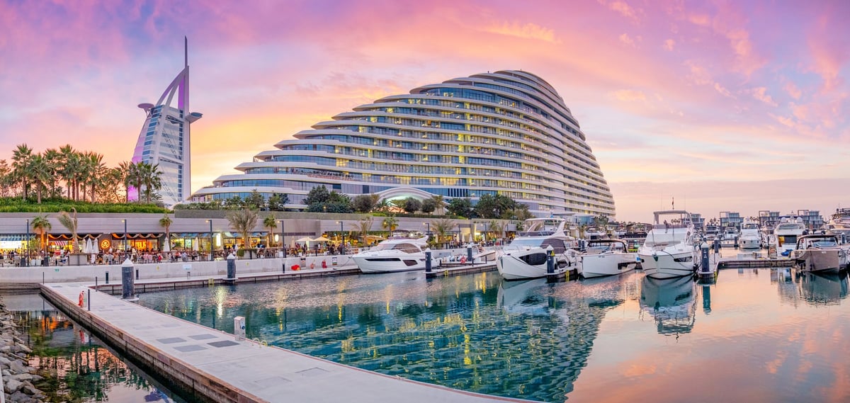Luxury marina with modern yachts and iconic hotels at golden hour