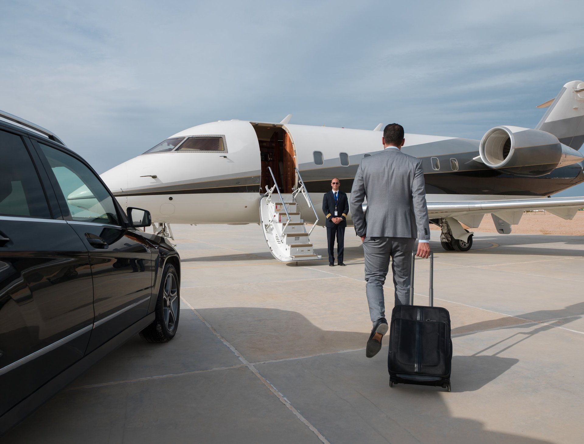 Business travellers walking across the tarmac towards a private jet at sunset