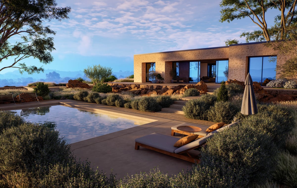 Contemporary stone villa featuring a luxury swimming pool, lounge chairs, and desert landscaping under a warm sunset sky