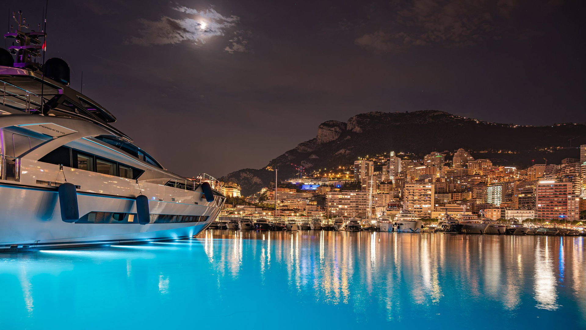 MONACO - JUNE 20, 2026: Night view of Port Hercule filled with luxury yachts and the illuminated Monte Carlo skyline in the background.