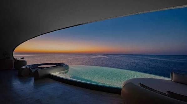 Sunset view from a luxury villa with infinity pool overlooking a calm lagoon and ocean horizon